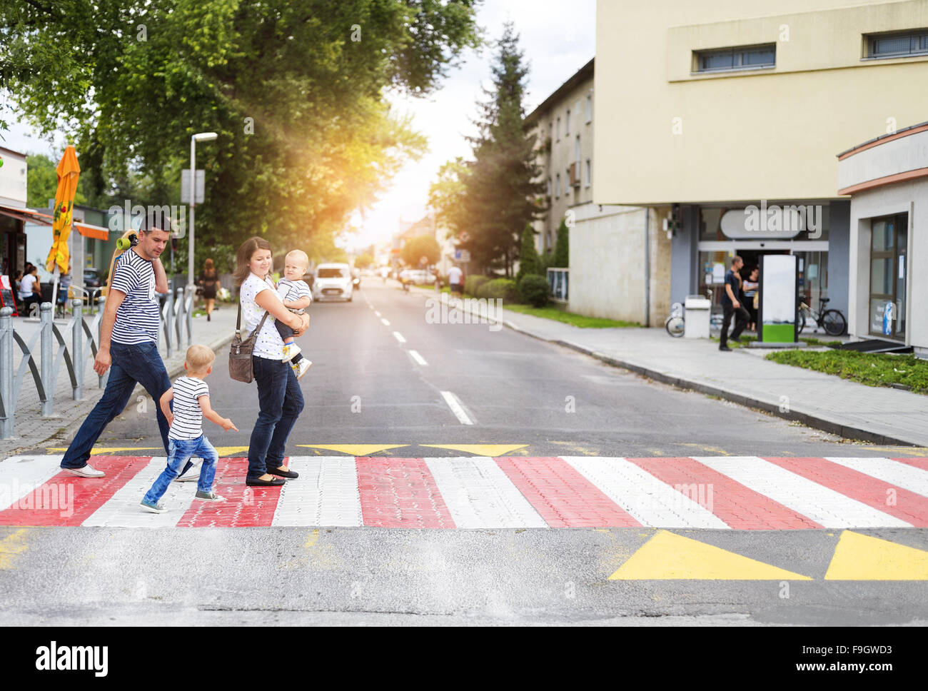 Young family with two boys in the city walking on a crosswalk Stock Photo