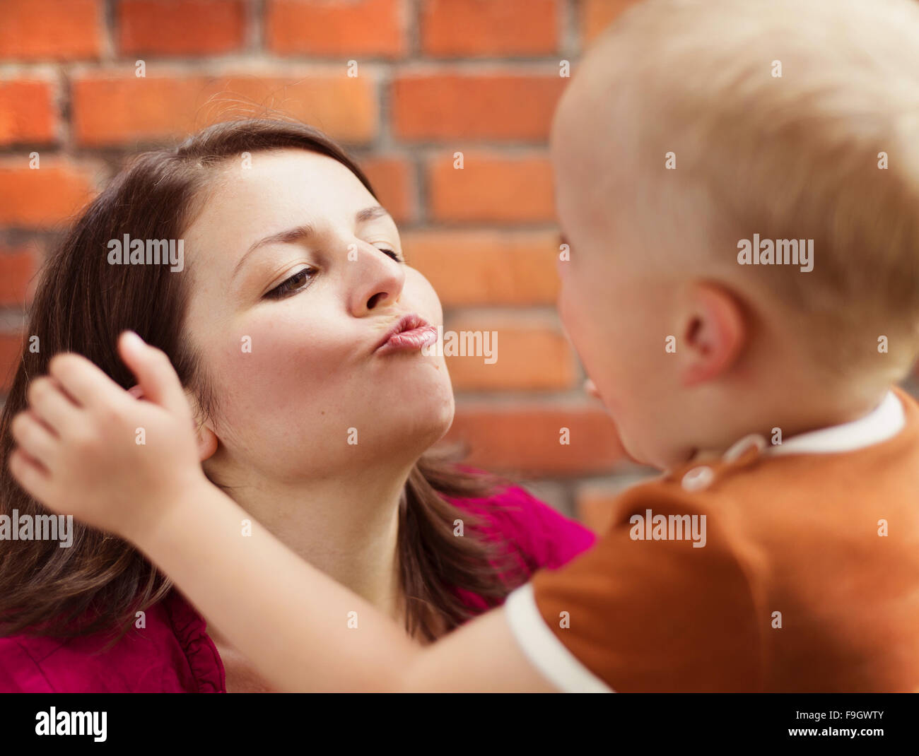 Mother and son making funny faces together on a brick wall background Stock Photo