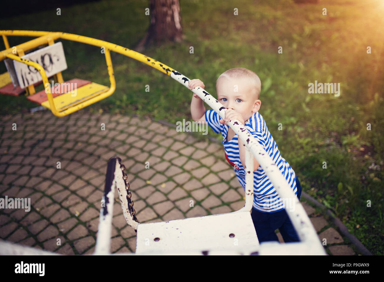 Cute little boy in a park on an old carousel. Stock Photo