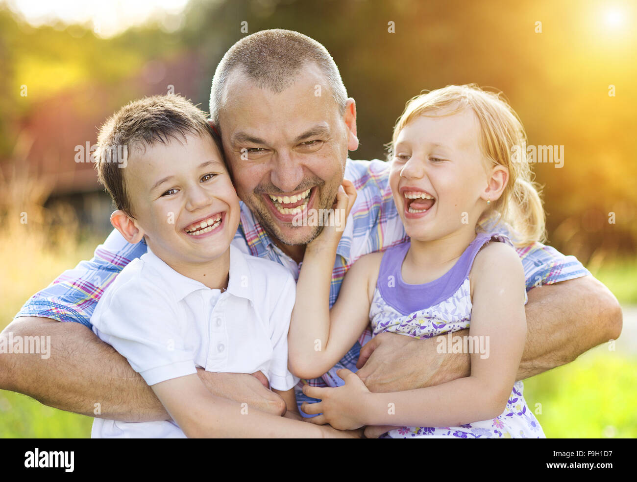 Father with his two children spending time together outside in green nature. Stock Photo