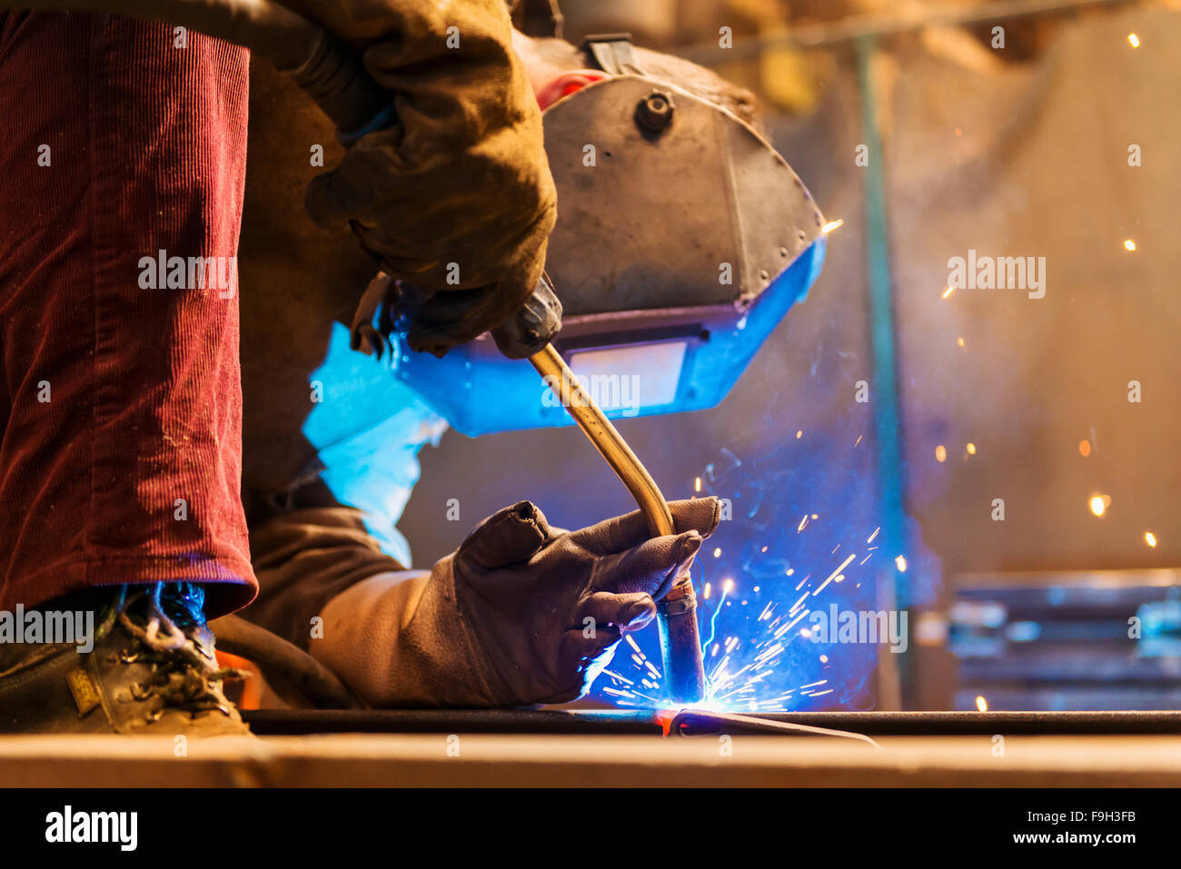 Young man with protective mask welding in a factory Stock Photo