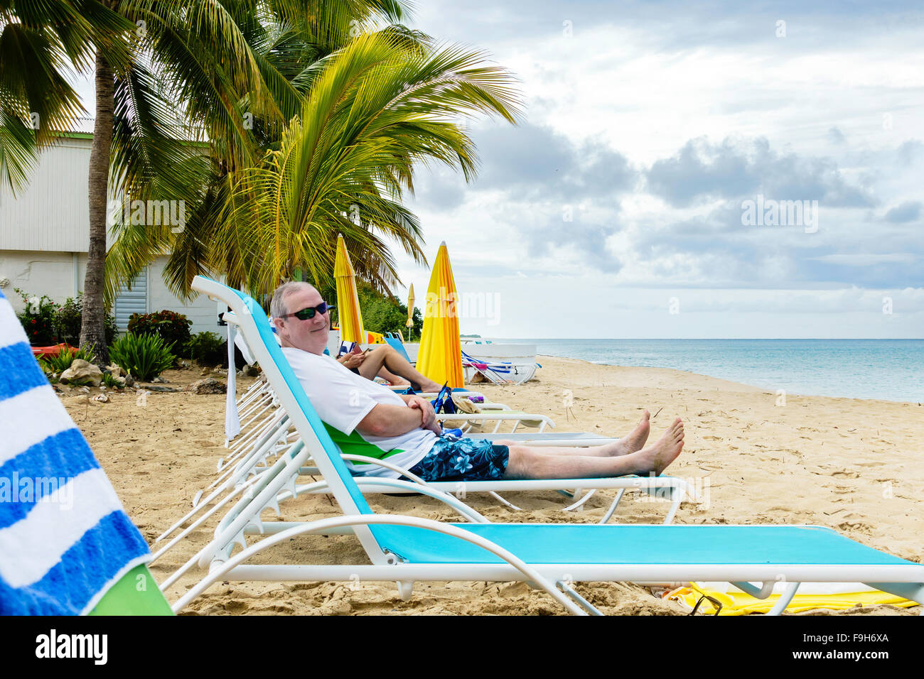 A 50 year old Caucasian man relaxes on a beach chair after a swim in the Caribbean at Cottages by the Sea resort in St. Croix, U.S. Virgin Islands. Stock Photo