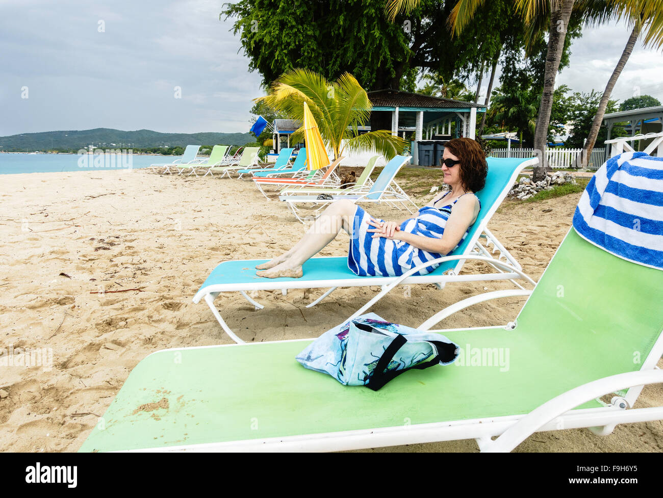 A 50 year old female guest at a beachside resort, wraps up in a beach towel and looks out to sea. St. croix, U.S. Virgin Islands. Stock Photo