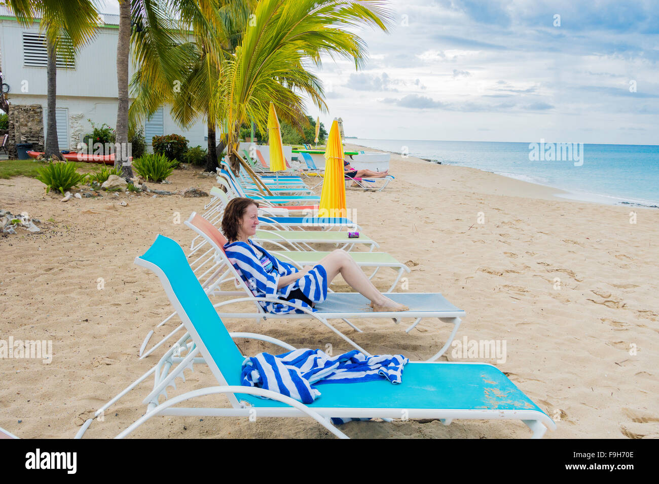 A 50 year old female guest at a beachside resort, wraps up in a beach towel and looks out to sea. Cottages by the Sea resort. Stock Photo
