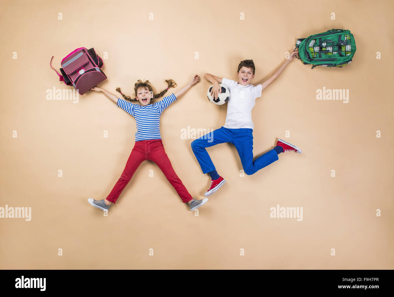 Children Rushing Happy children running to school in a hurry. Studio shot on a beige ...
