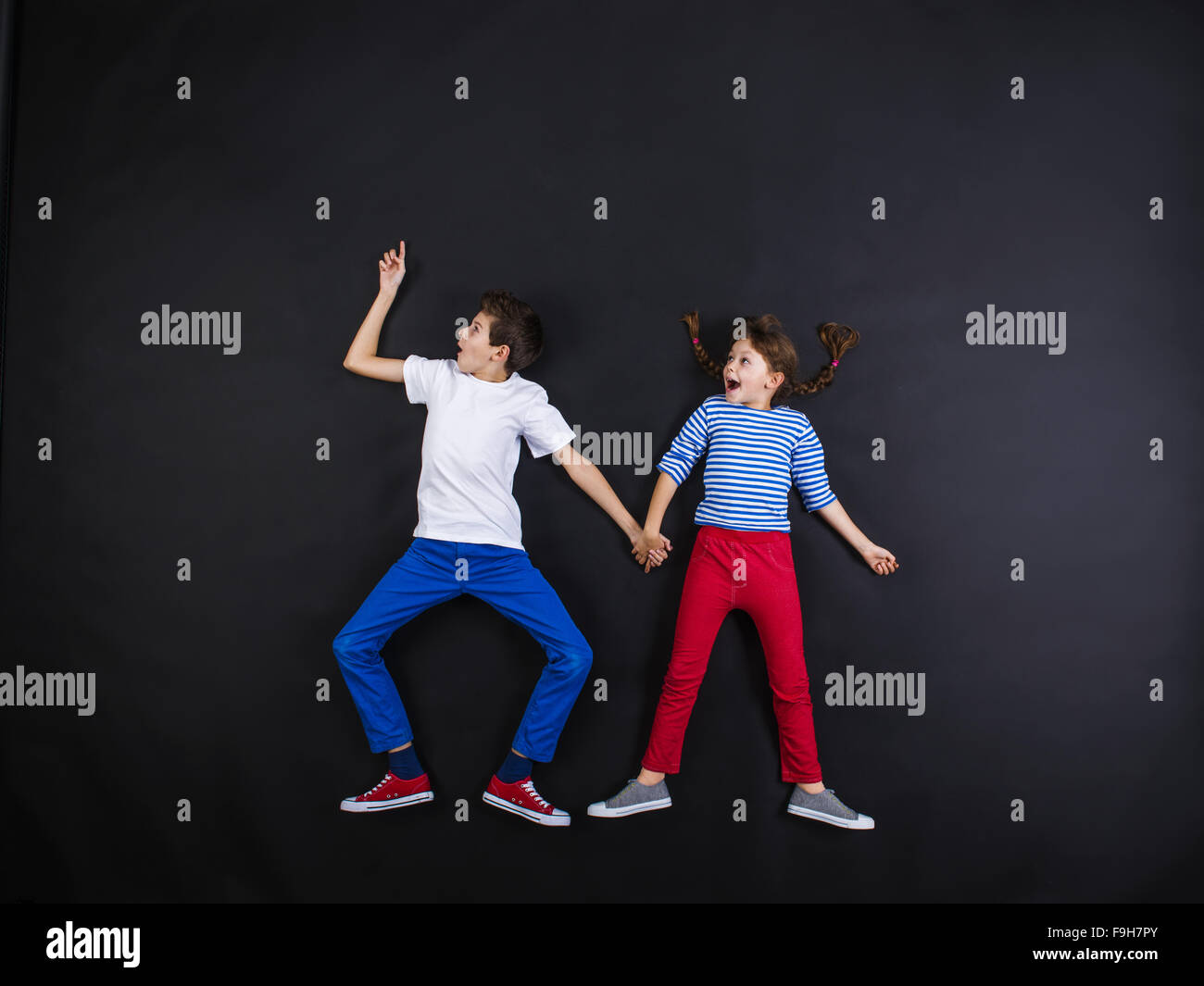 Playful young siblings laughing and having fun together. Studio shot on ...