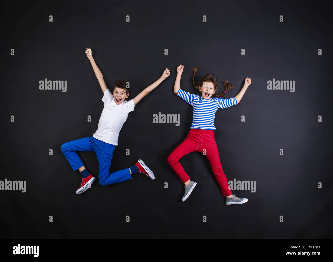Playful young siblings laughing and having fun together. Studio shot on ...