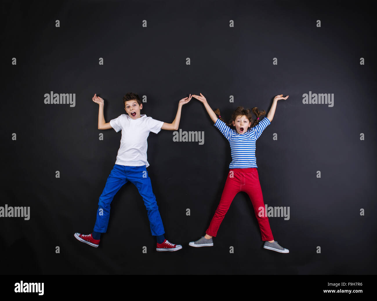 Playful young siblings laughing and having fun together. Studio shot on ...