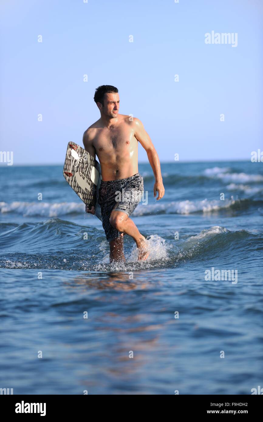 Portrait of a strong young surf man at beach on sunset in a ...