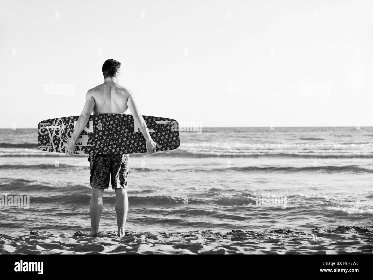 Portrait of a strong young  surf  man at beach on sunset in a contemplative mood with a surfboard Stock Photo