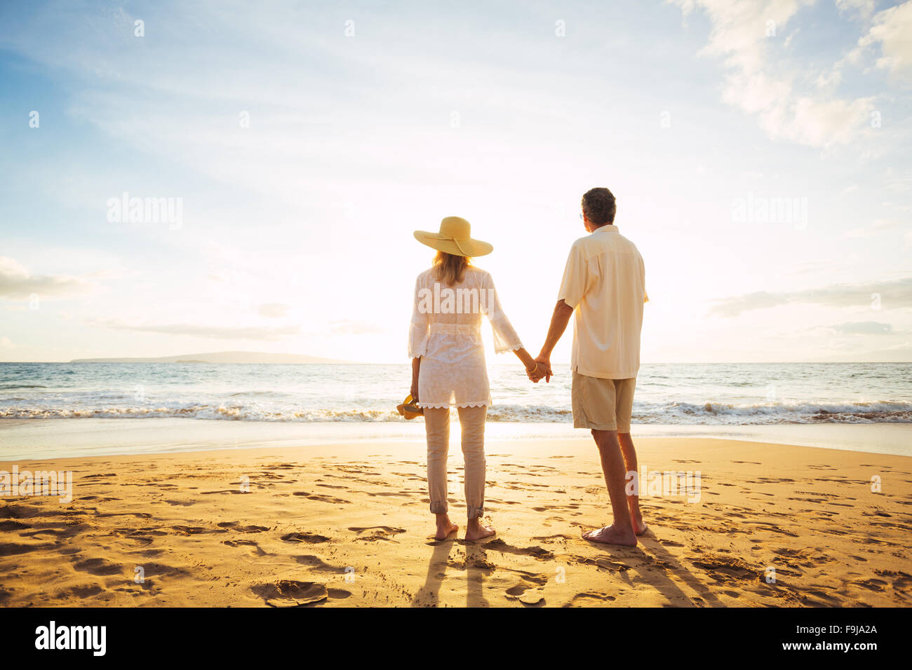 Happy Romantic Middle Aged Couple Enjoying Beautiful Sunset on the Beach. Travel Vacation Retirement Lifestyle Concept. Stock Photo
