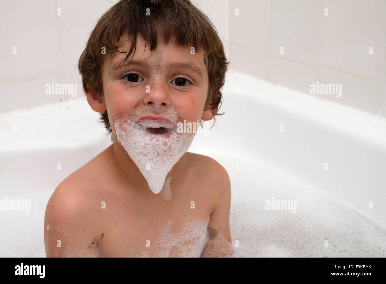 Toddler boy (5 years old) having fun with bubbles in the bath. Stock Photo