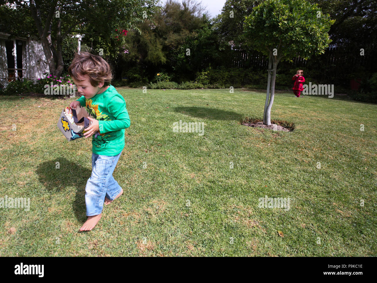 Young children collect easter eggs on an easter hunt in a garden. Stock Photo