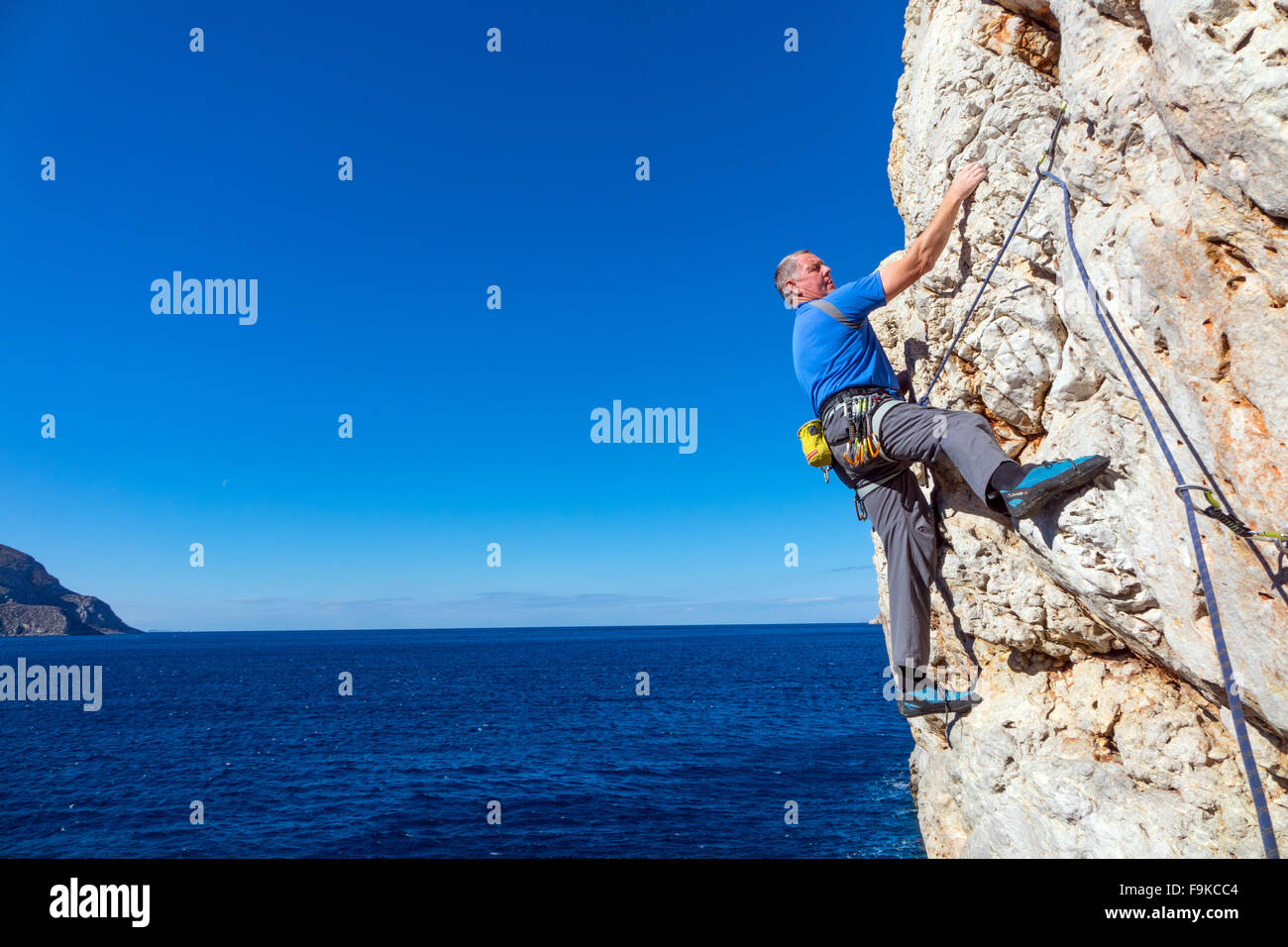 Rock climber rock climbing on steep cliff face Stock Photo