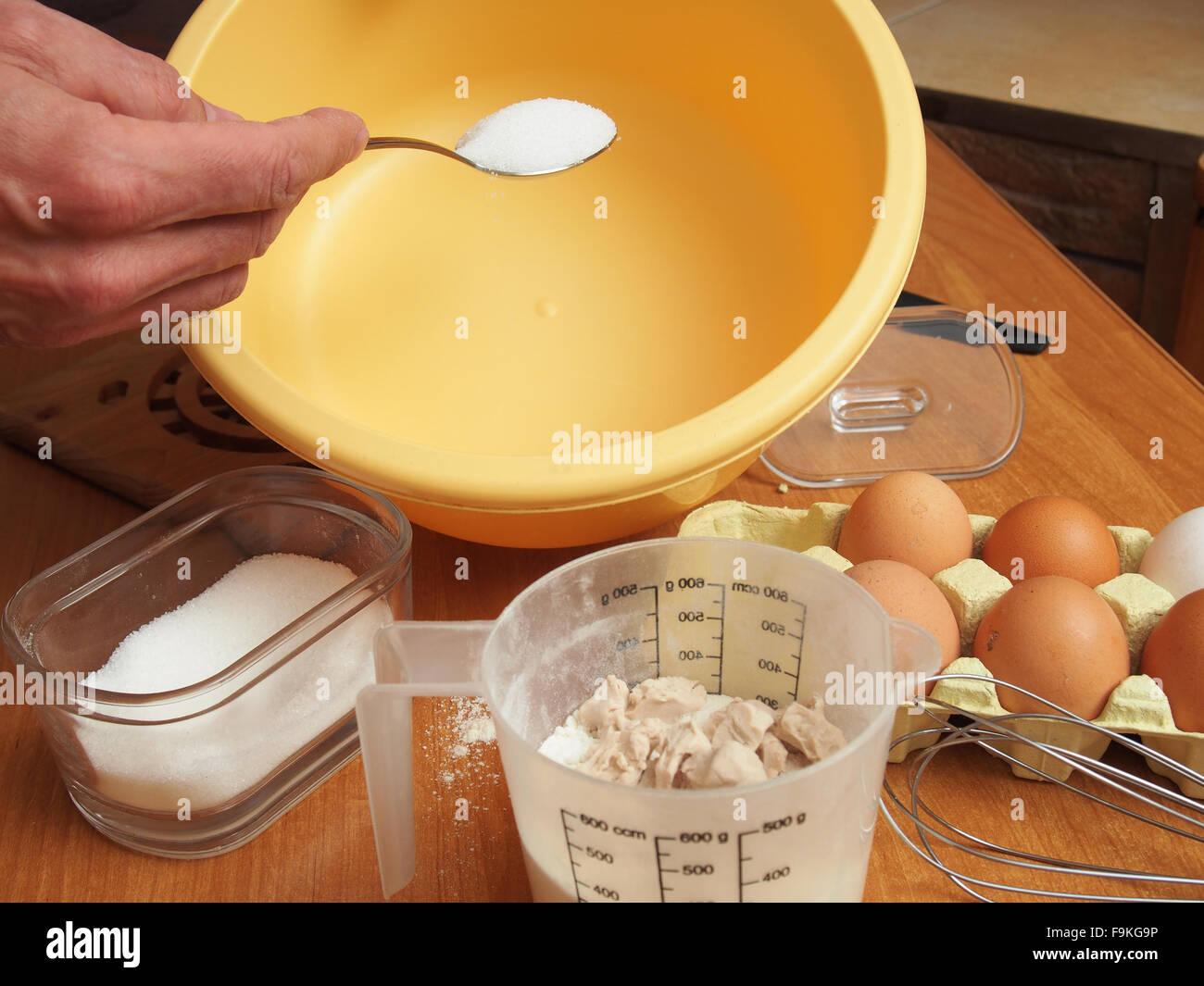 Adding sugar into mixing bowl. Making yeast pancakes (crepes). Stock Photo