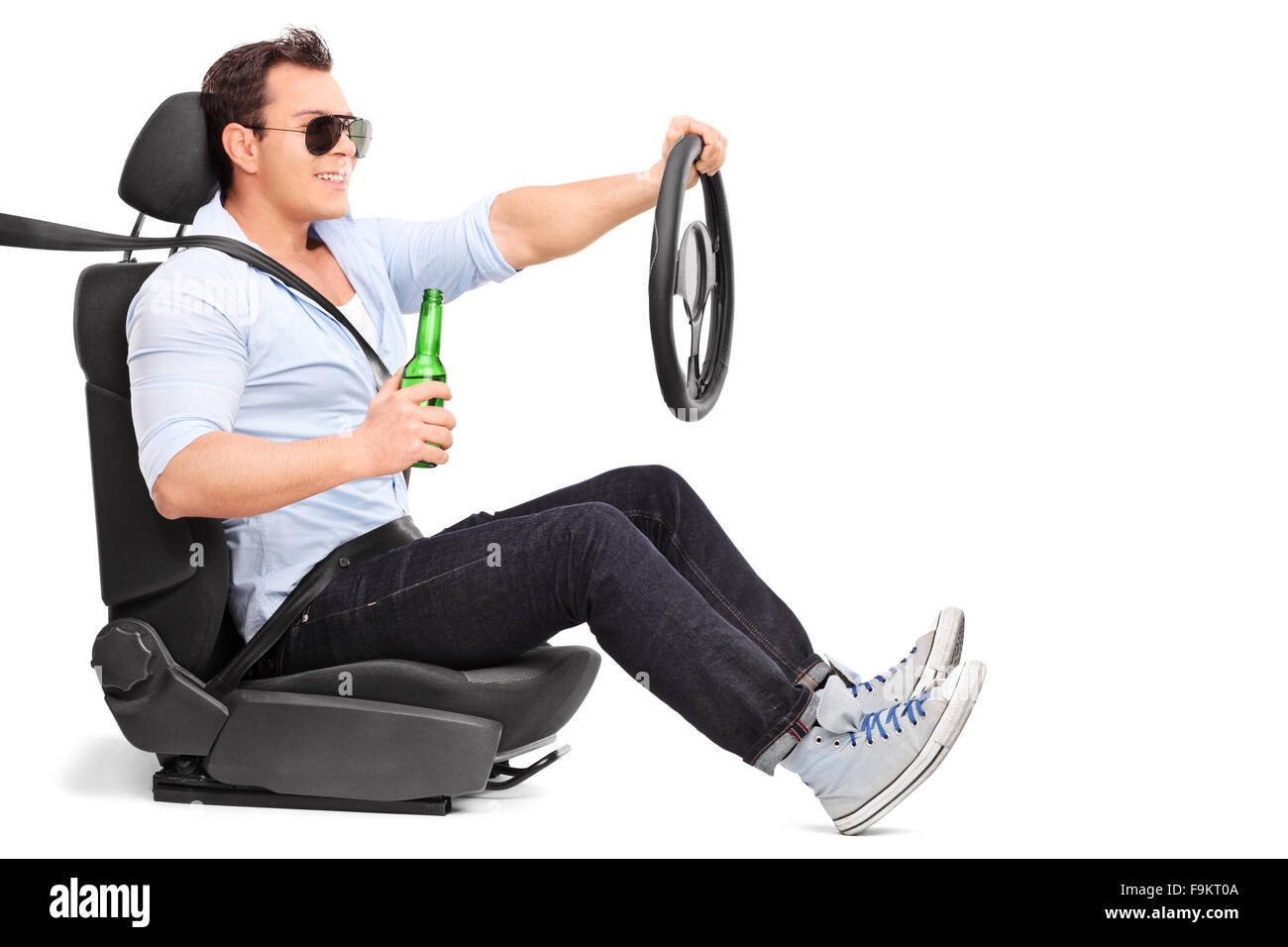 Careless young man driving and holding a bottle of beer isolated on white background Stock Photo