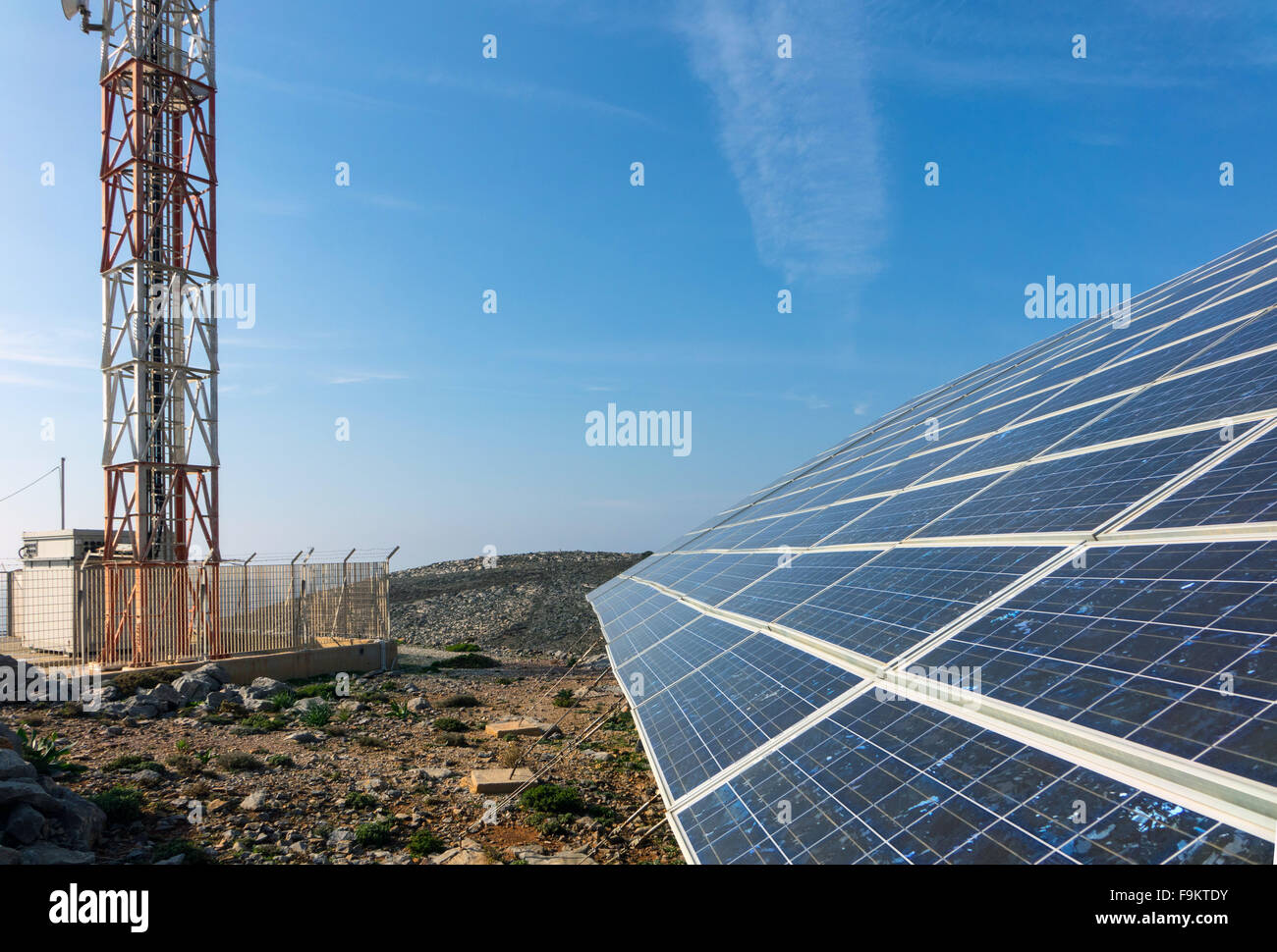 Solar panels and mobile phone mast against blue sky Stock Photo