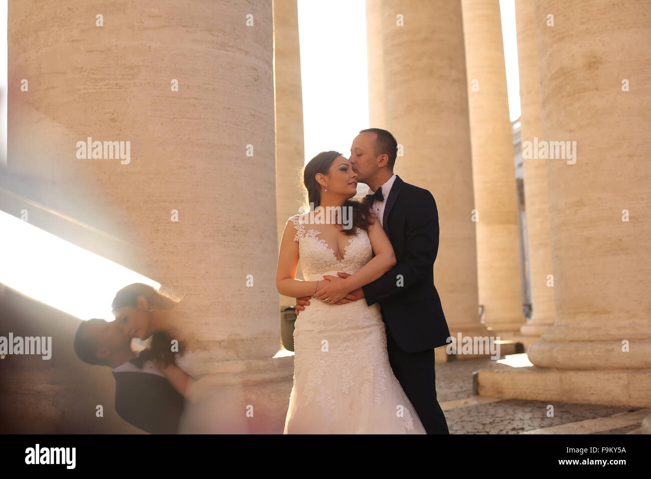 Beautiful bridal couple embracing and kissing near columns Stock Photo ...