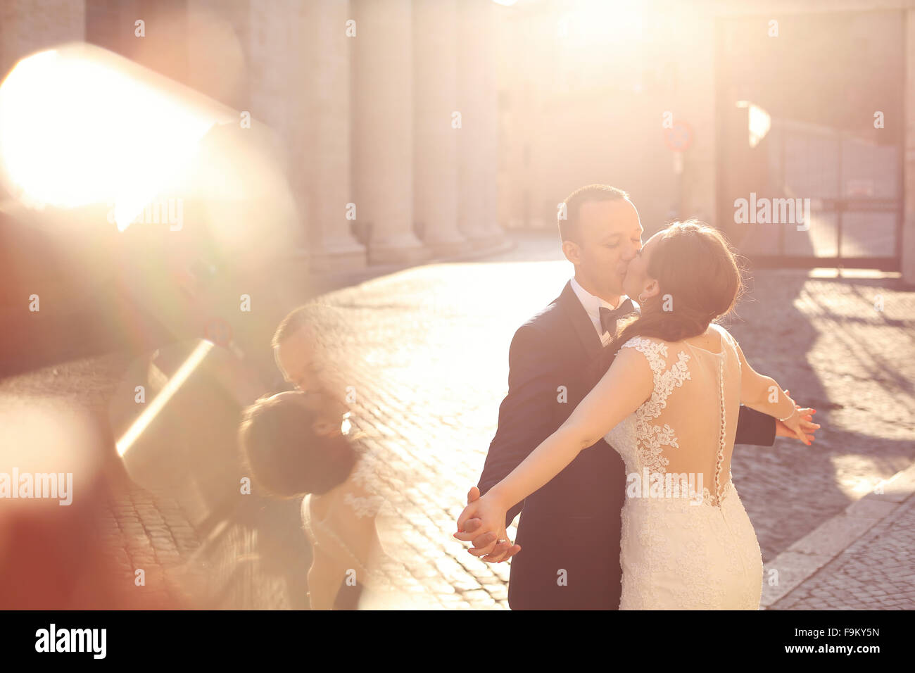 Beautiful bridal couple embracing and kissing near columns Stock Photo ...
