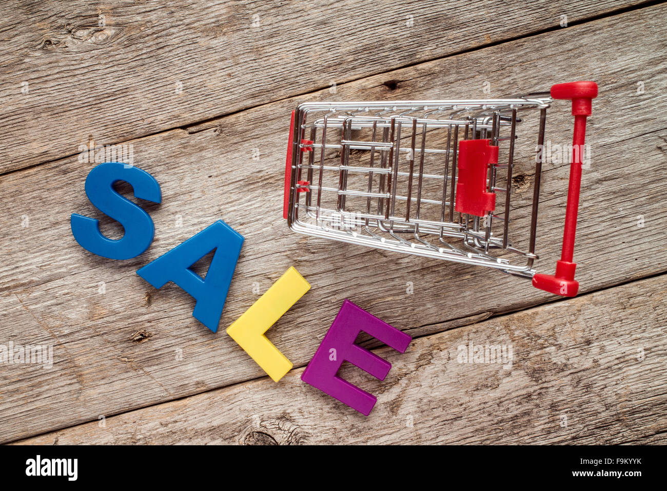 Shopping cart and plastic letters spelling SALE on wooden background ...