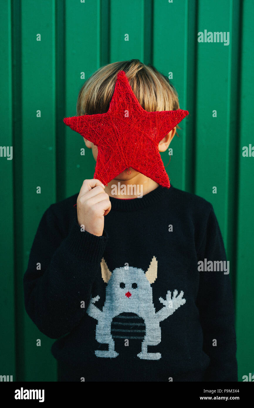 6 years old boy holding a red star in front of his face Stock Photo