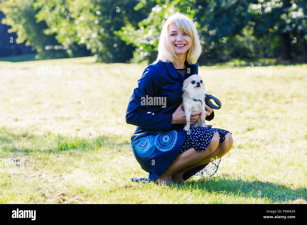 Pretty blonde lady holding her scared chihuahua Stock Photo