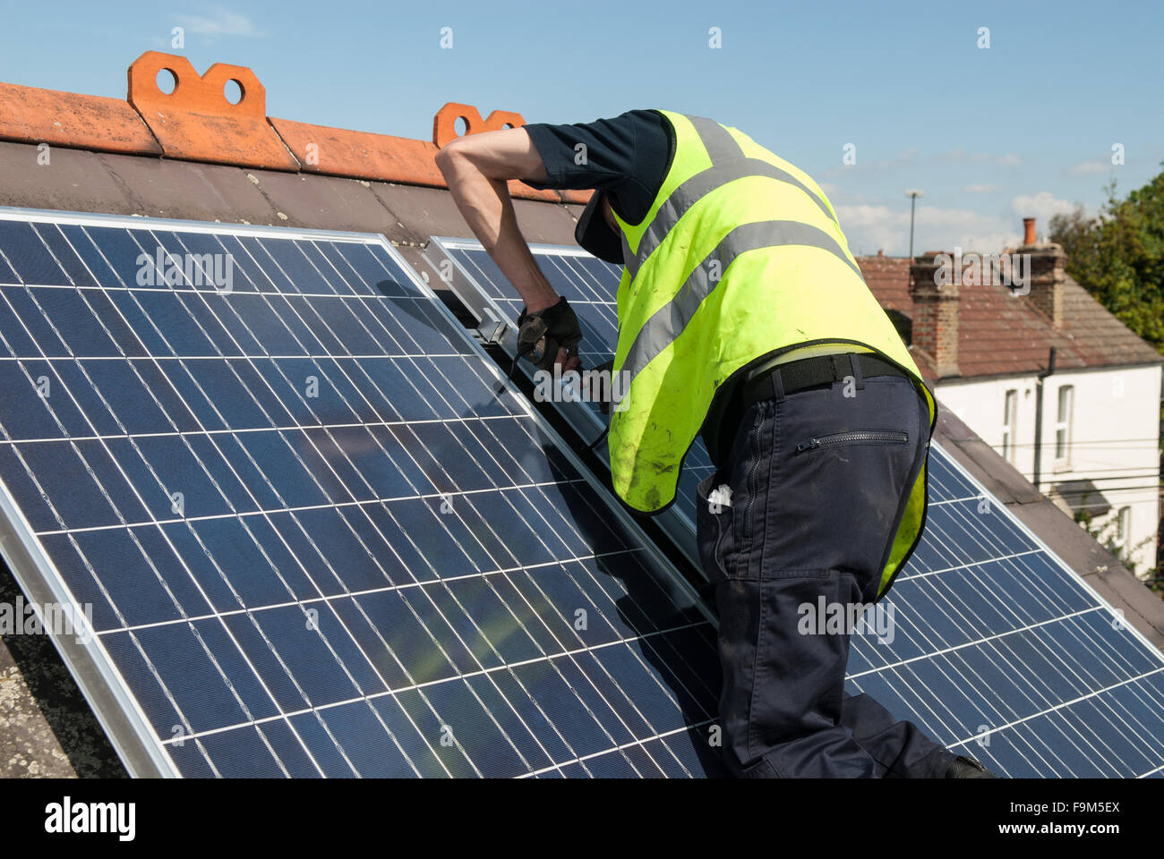 Workers install photovoltaic solar panels on the slate roof of a
