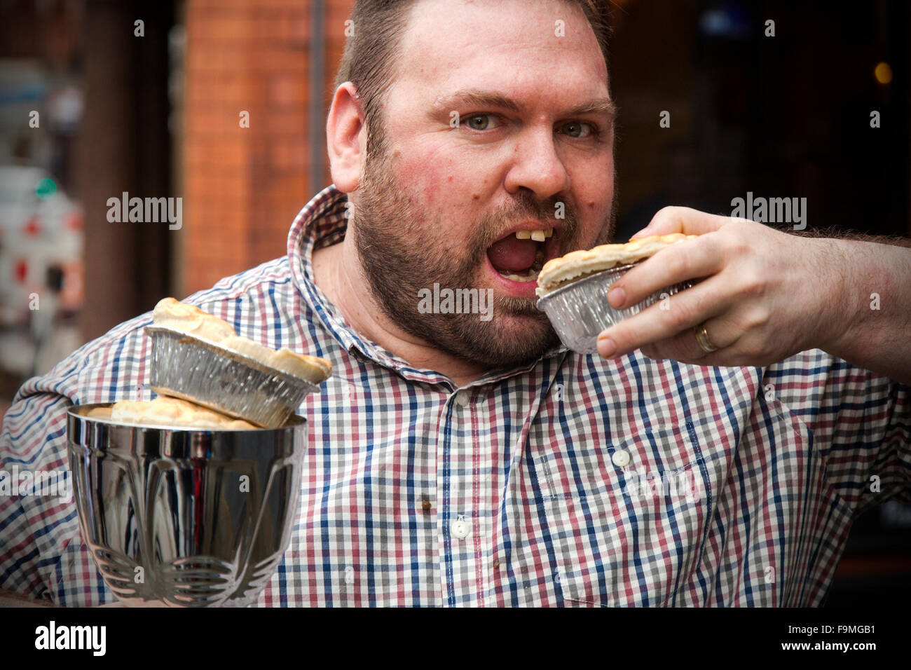 Wigan, Lancashire, UK. 17th December, 2015. The World Pie Eating Championships at Harry’s Bar in Wigan, Wallgate. The winner, Martin Appleton is the person who managed to eat a standard pie fastest.  Martin scored an impressive 38.2 seconds.  The pies are 12cm in diameter and 3.5 cm deep with a beef and potato filling.  The competition, held exactly at Pie Noon saw contestants attempting to consume Wigan’s most famous contribution to cuisine as fast as possible to take home the title of World Champion and lift the Bradley Piggins Trophy. Stock Photo