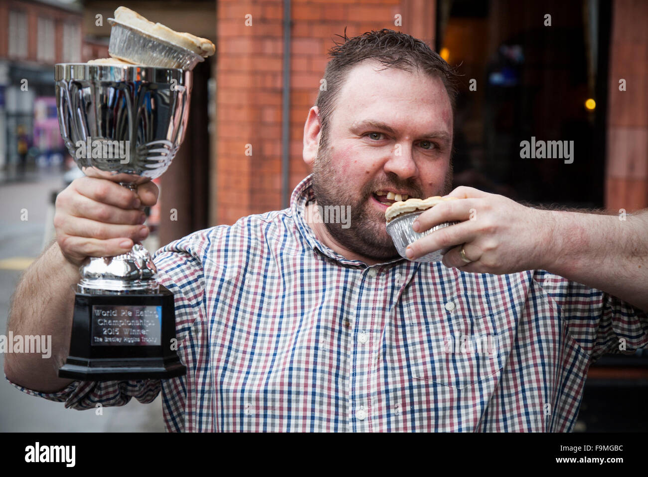 Wigan, UK. 17th December, 2015. The World Pie Eating Championships at Harry’s Bar in Wigan, Wallgate. The winner, Martin Appleton is the person who managed to eat a standard pie fastest.  Martin scored an impressive 38.2 seconds.  The pies are 12cm in diameter and 3.5 cm deep with a beef and potato filling.  The competition, held exactly at Pie Noon saw contestants attempting to consume Wigan’s most famous contribution to cuisine as fast as possible to take home the title of World Champion and lift the Bradley Piggins Trophy. Credit:  Mar Photographics/Alamy Live News Stock Photo