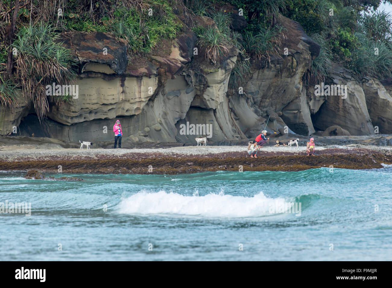 Anglers fishing from rocks on Tip of Borneo beach Sabah East Malaysia Island of Borneo Stock Photo