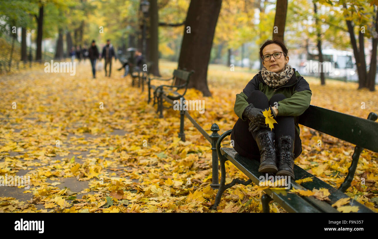 A woman sitting on a bench in autumn Park Stock Photo - Alamy