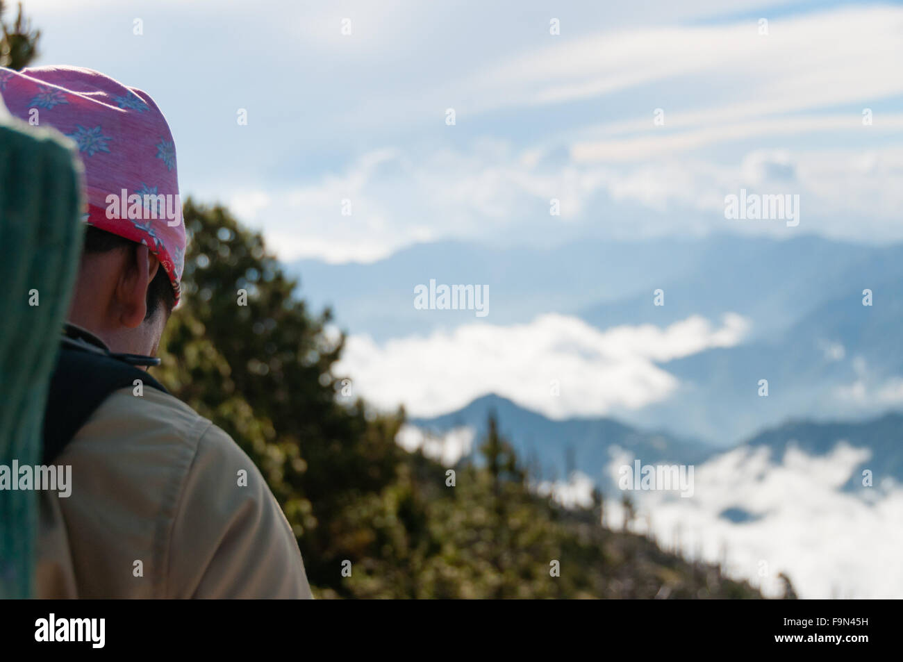 Young man with bandana from the side walking towards cloudscape and mountain Tajamulco Stock Photo