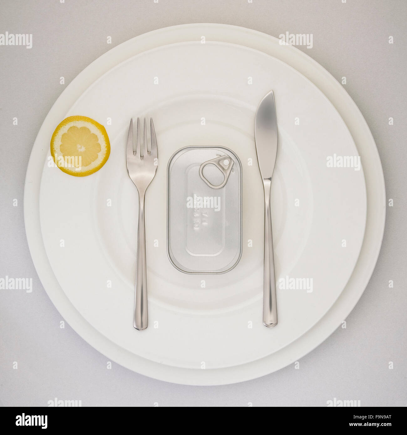 canned fish and lemon on an elegant plate – what's left after the financial crises Stock Photo
