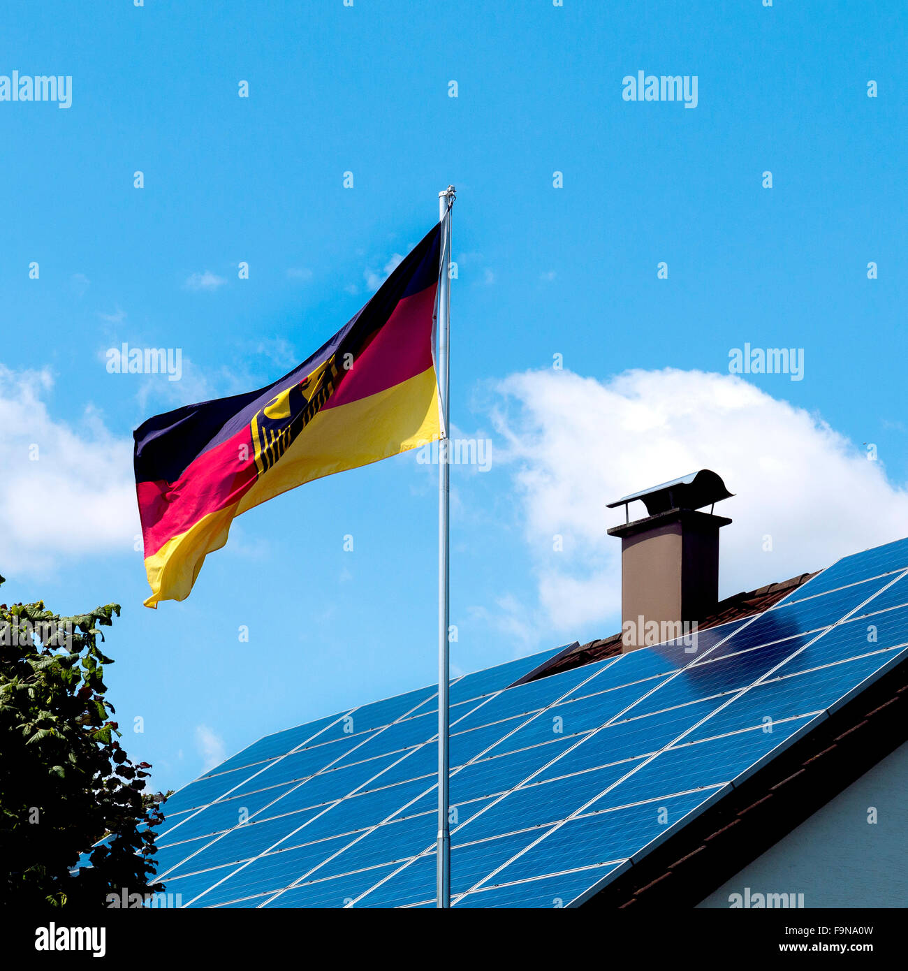 House roof with solar panels, flag of Germany in front, energy transition in Germany Stock Photo