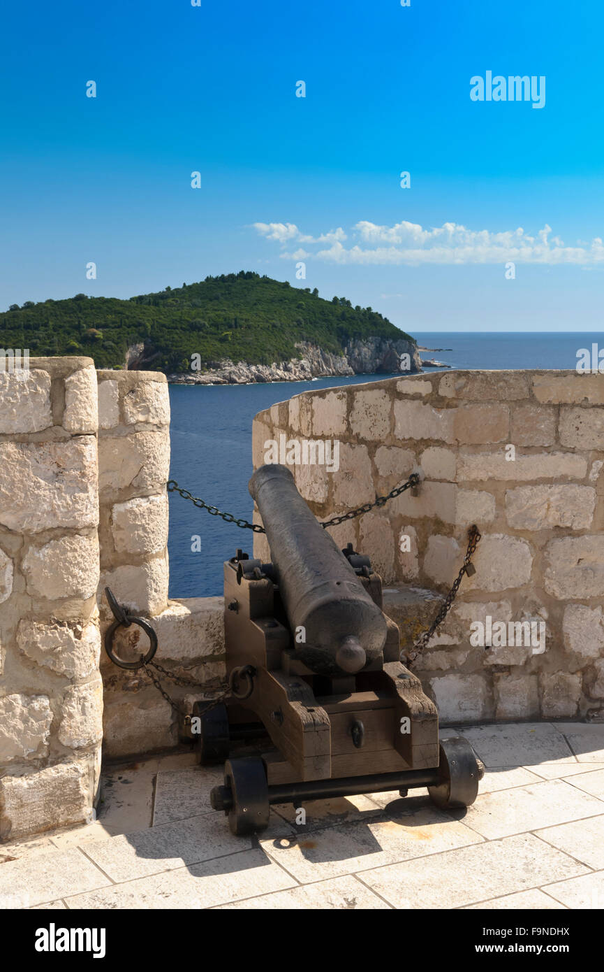 An old cast iron cannon aiming towards the sea appearing within a gap on the wall of the fortress, Dubrovnik, Croatia. Stock Photo