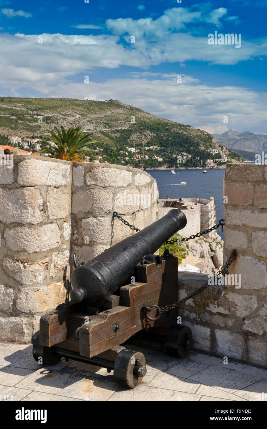 An old cast iron cannon aiming towards the sea appearing within a gap on the wall of the fortress, Dubrovnik, Croatia. Stock Photo
