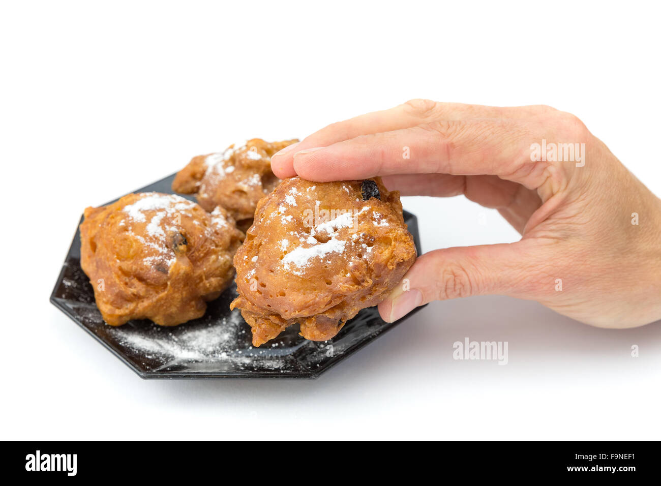 Hand showing dutch oliebol or fritter with icing sugar isolated on white background Stock Photo