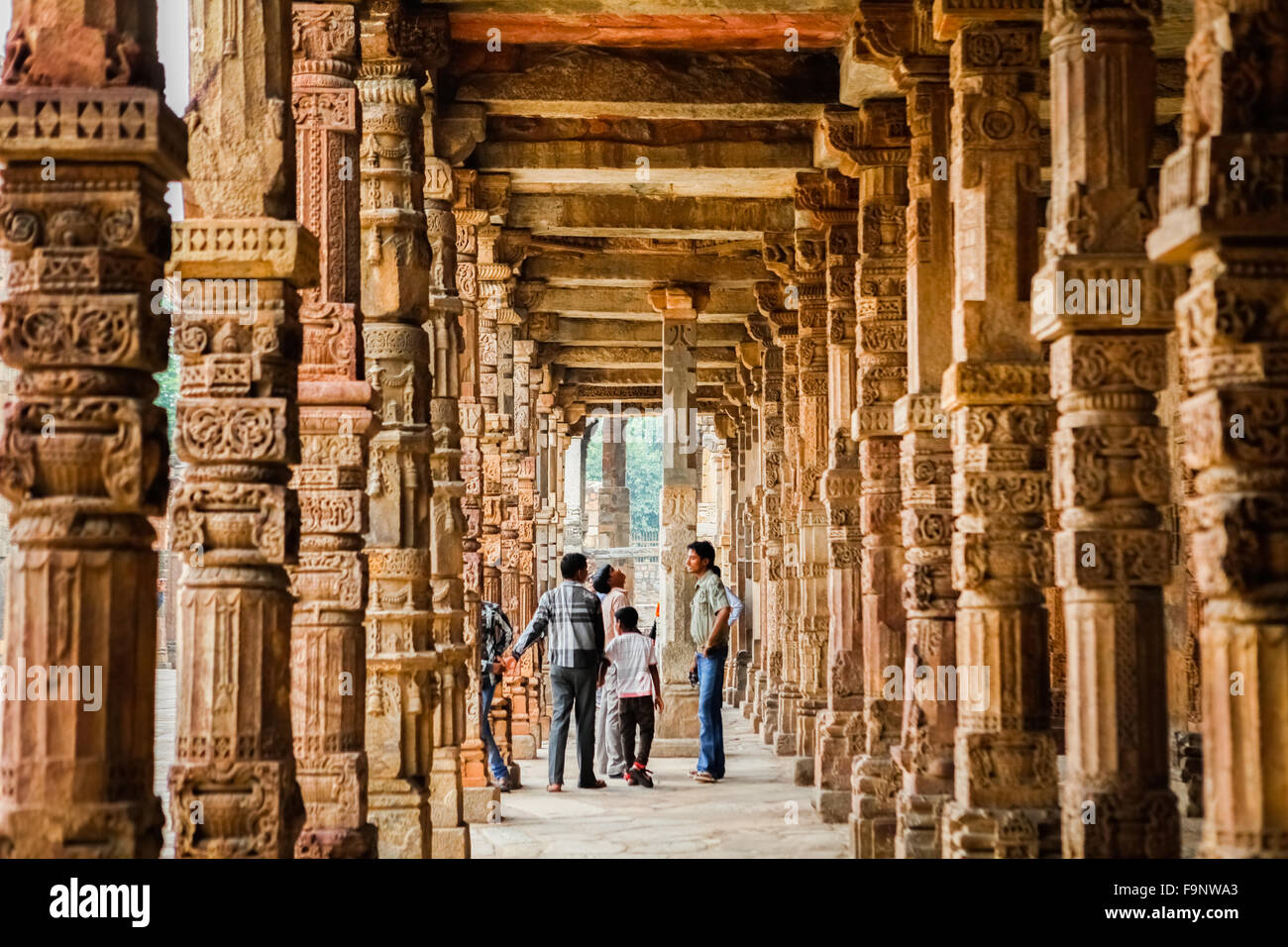 Local tourists admiring intricate stone carvings on the cloister columns at Quwwat ul-Islam Mosque inside Qutb complex, Delhi. Stock Photo
