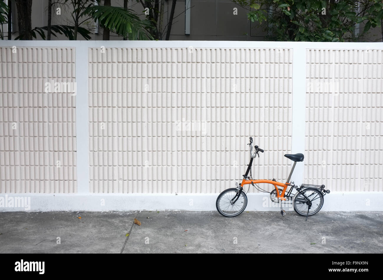 Orange bicycle parks in front of wall Stock Photo