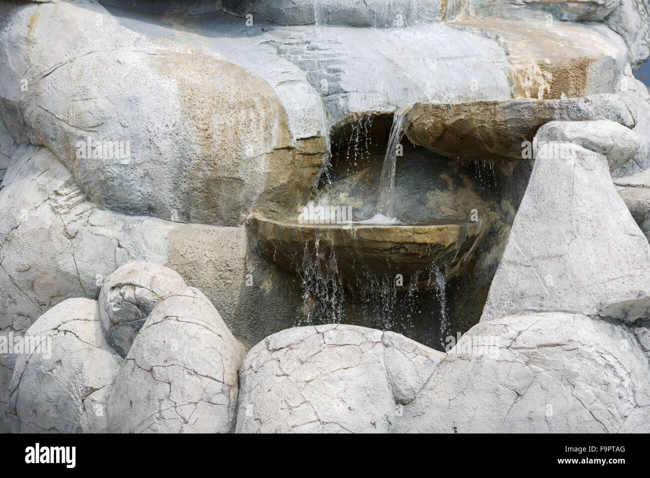 Close-up of a trickle of water flowing among the stones. Small artificial waterfall. Stock Photo