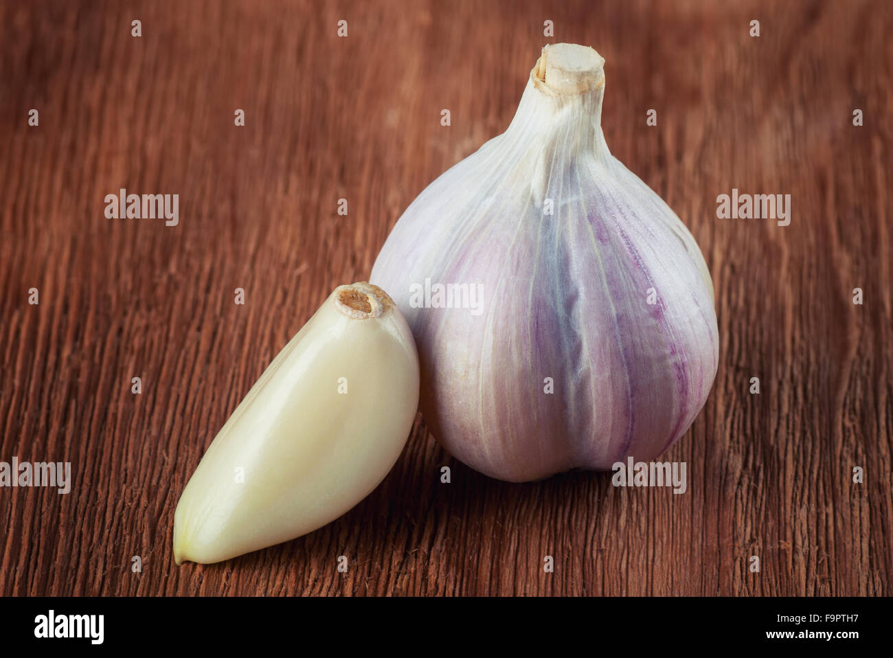 Fresh head of garlic and clove on brown wooden table Stock Photo