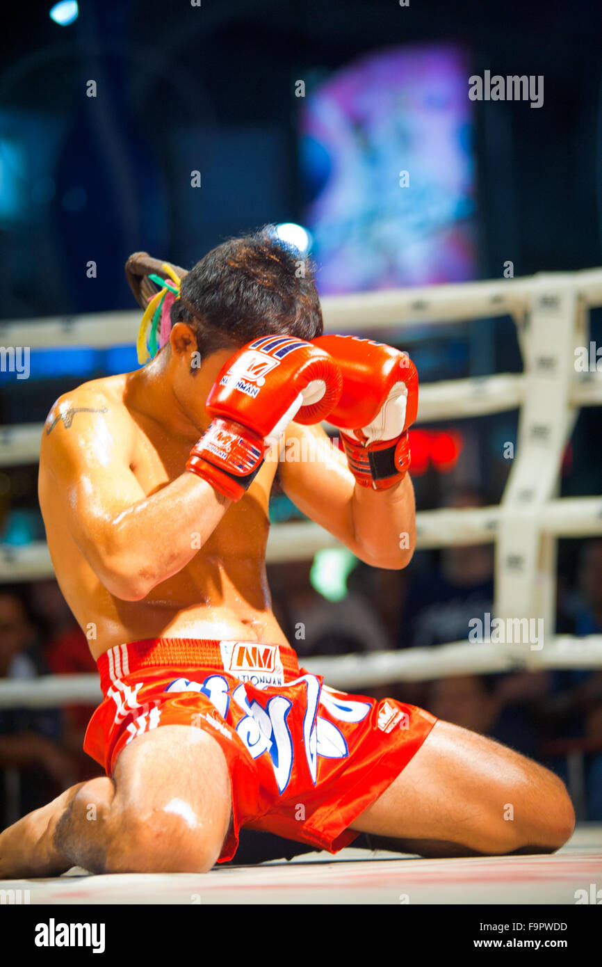 Male muay thai kickboxer kneeling and covering his face with gloves during traditional pre-fight ritual called the wai khru Stock Photo