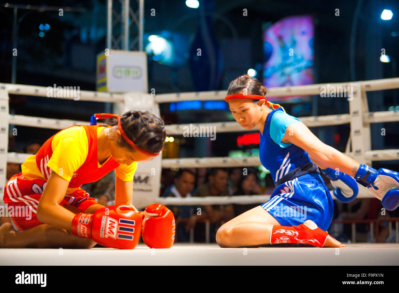 Two female muay thai fighters side by side kneeling, bowing, performing kickboxing ritual dance called the wai khru before match Stock Photo