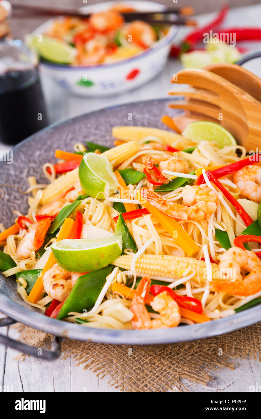 A healthy stir-fry of shrimp and vegetables served over noodles Stock