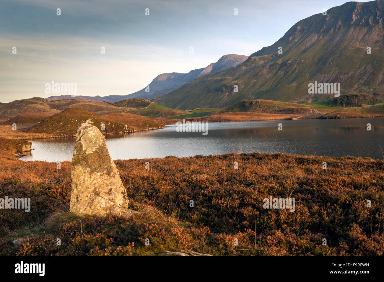 Late autumn sun lights a boundary stone with a background of Cregennan lakes and Cader idris mountain range. Stock Photo