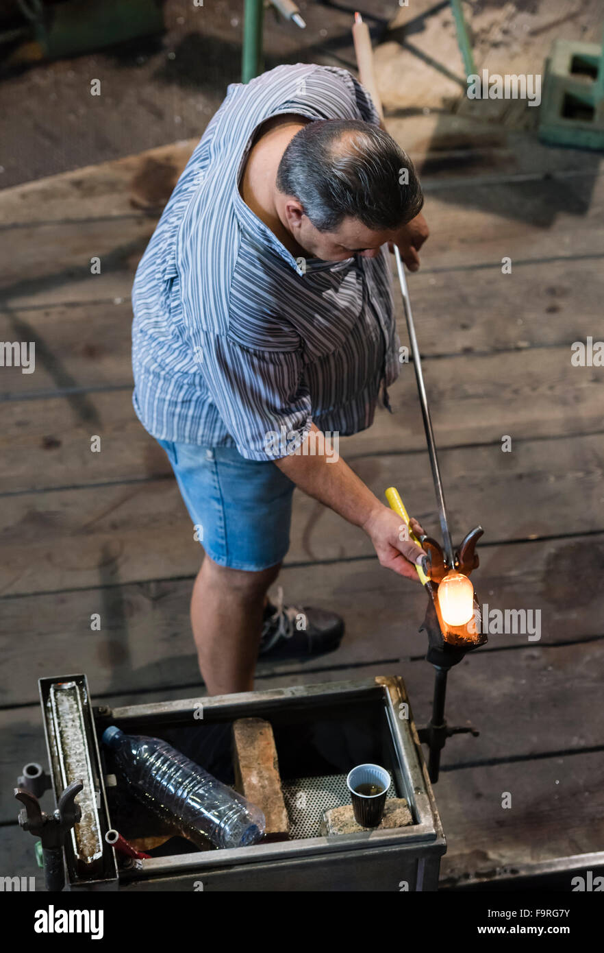 A glassblower at work in front of the furnace of the traditional glassblowing manufacture at Hergiswil, Switzerland. Stock Photo