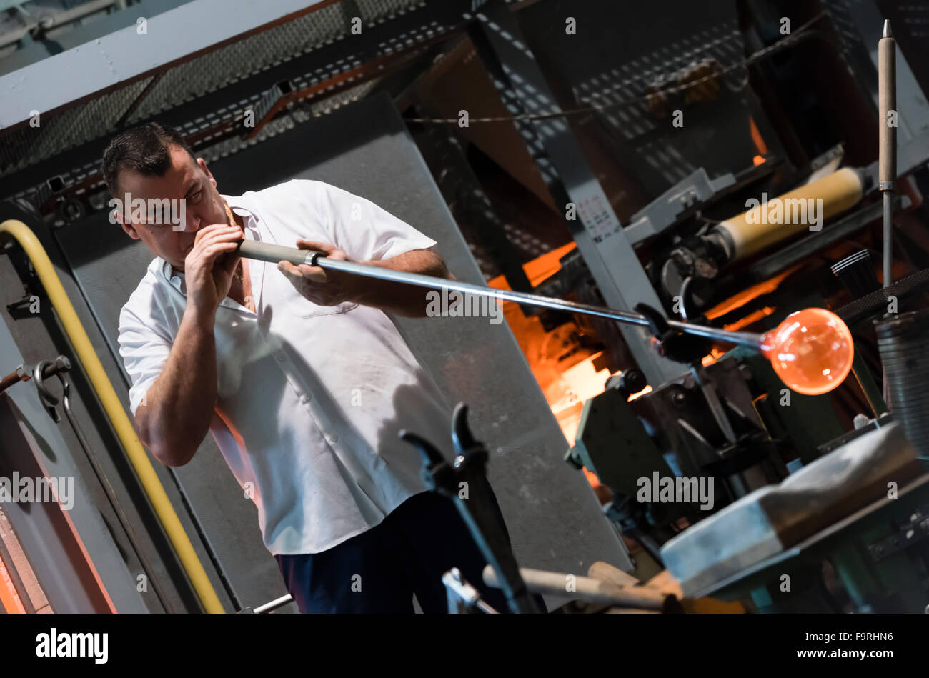 A glassblower at work in front of the furnace of the traditional glassblowing manufacture at Hergiswil, Switzerland. Stock Photo