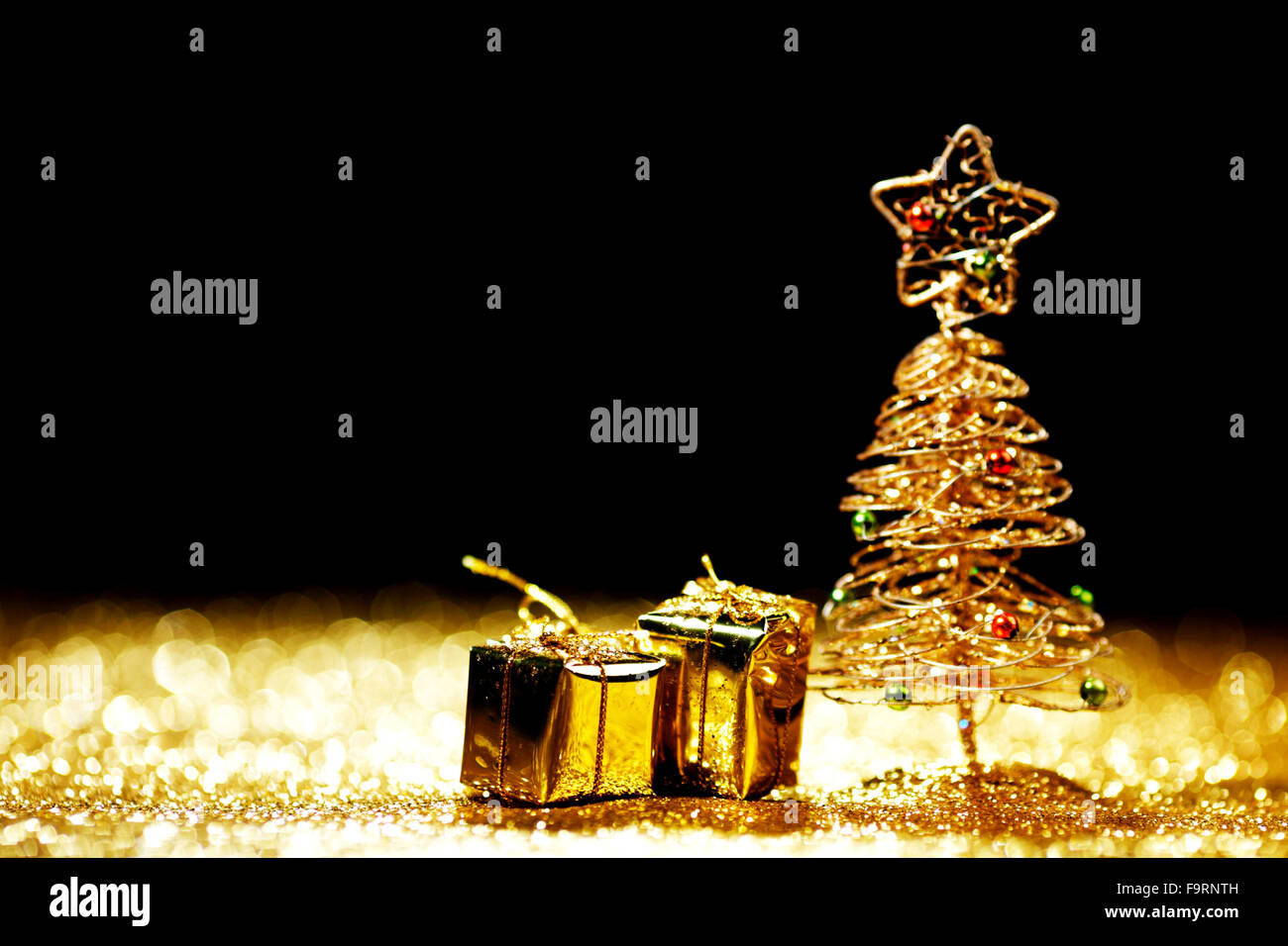 Beautiful golden decorative christmas tree and gifts on golden glitter ...
