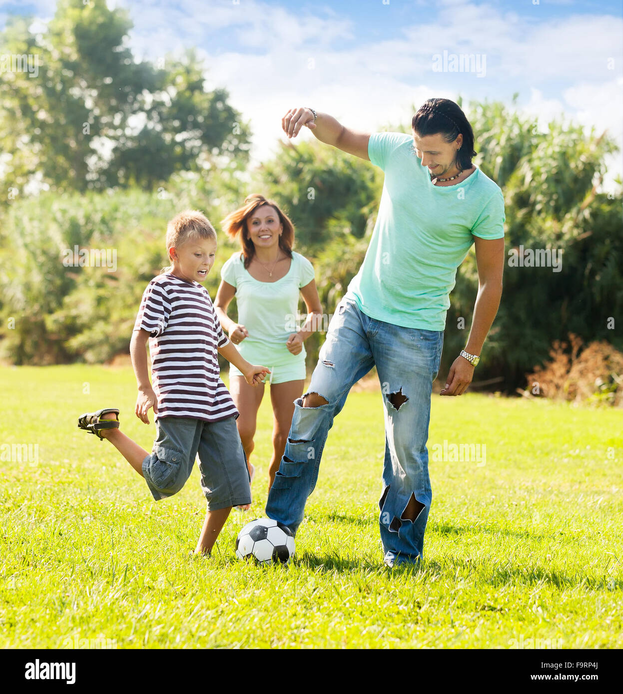 Happy family of three playing with soccer ball at summer park Stock ...