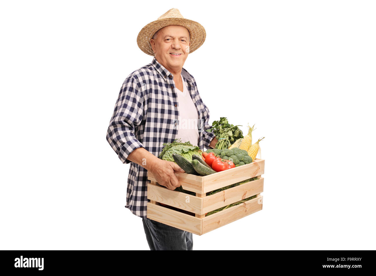 Cheerful mature farmer holding a crate full of fresh vegetables and ...